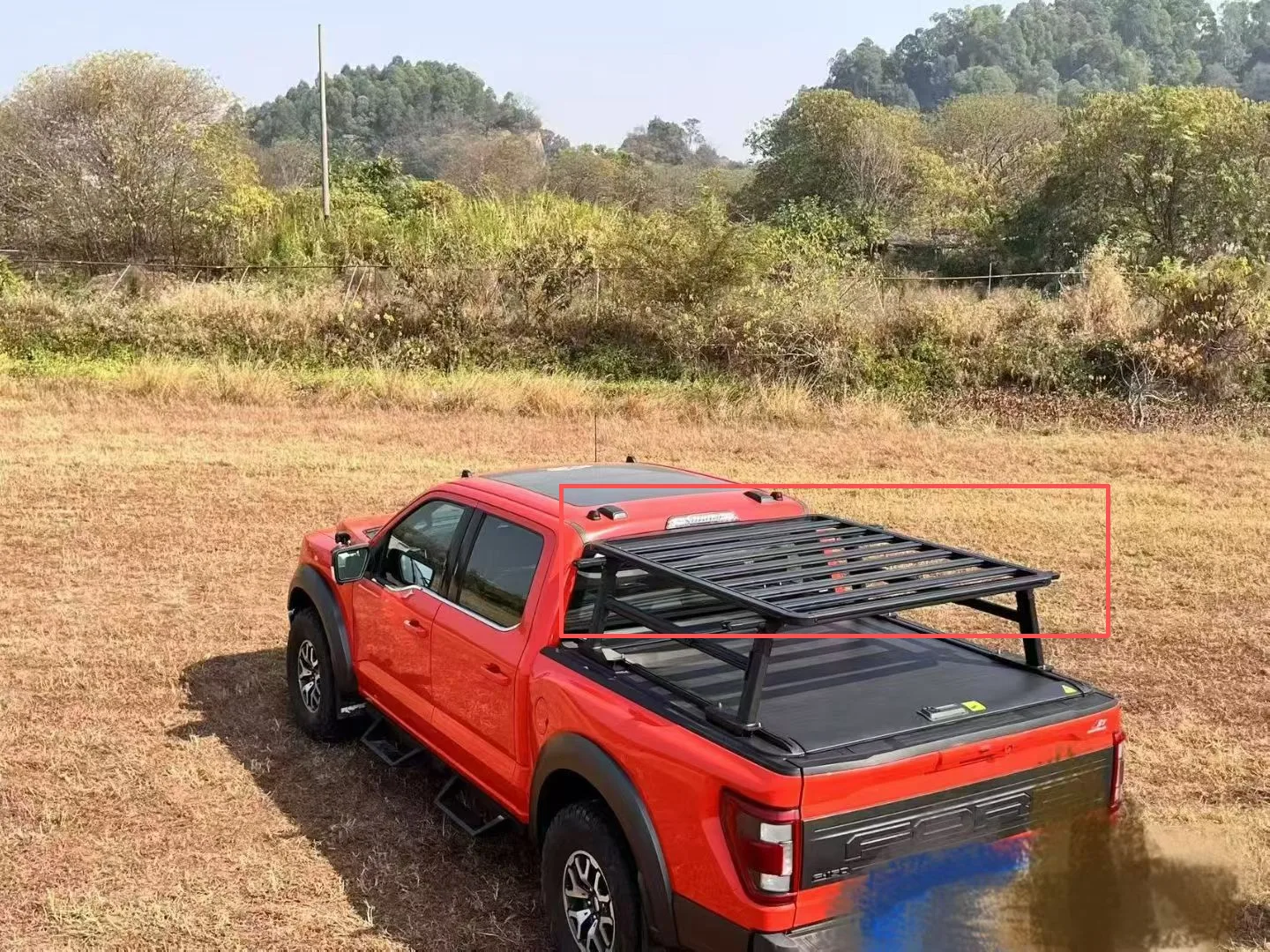 Black platform mounted over the bed of an unidentified red pickup, viewed from above