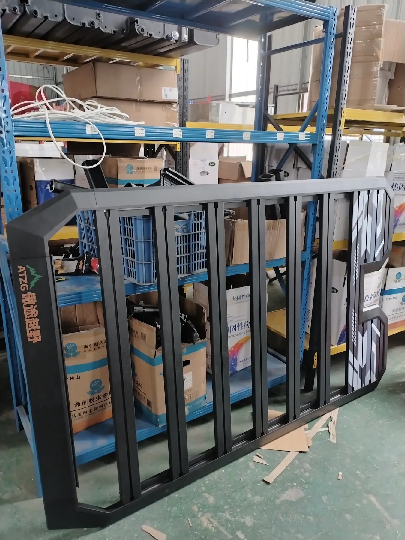 Black aluminum roof rack standing upright in a workshop storage area